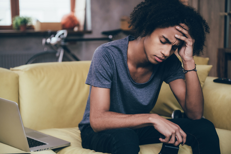 Guy sitting on couch sitting with his forehead in his hand
