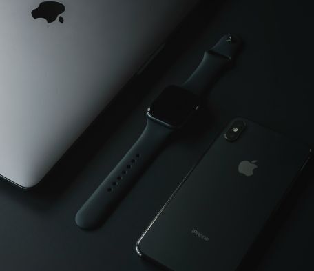 An iPad, Apple Watch, and iPhone laying side-by-side.